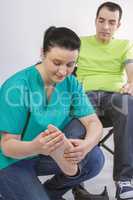 Physiotherapist massaging foot of young man in wheelchair