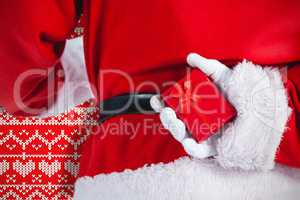 Composite image of santa claus holding gift box behind his back