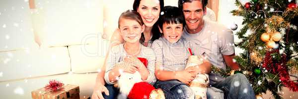 Composite image of happy family at christmas time holding lots of presents