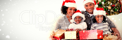 Composite image of family holding christmas presents