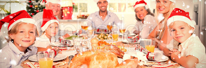 Composite image of happy family wearing santa hats around the dinner table