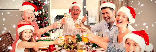 Composite image of family in santas hats toasting wine glasses at dining table