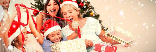 Composite image of happy family at christmas opening gifts together