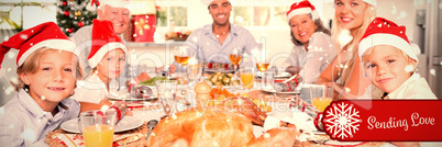 Composite image of happy family wearing santa hats around the dinner table