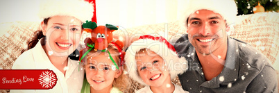 Composite image of portrait of a happy family with christmas hats sitting on the sofa