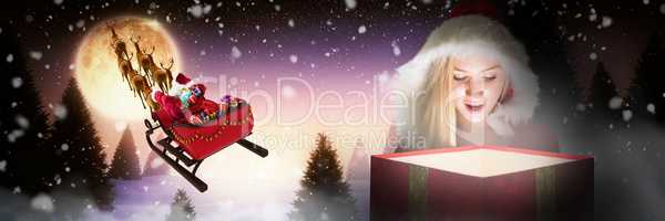 Composite image of festive blonde looking into glowing gift