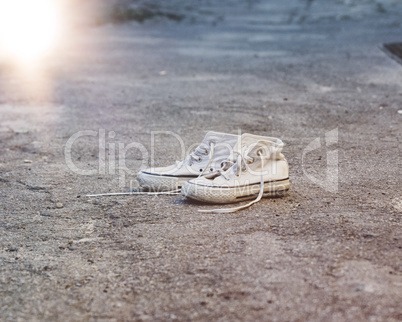 pair of very old white sneakers with untied laces