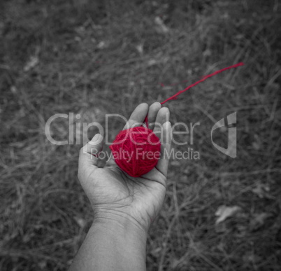 red wool clew in human hand, top view