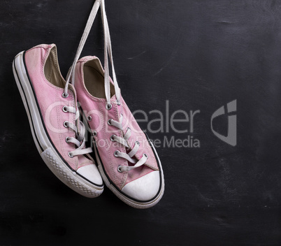 pair of pink textile sneakers hanging on a lace