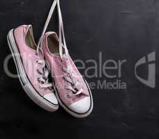 pair of pink textile sneakers hanging on a lace