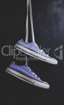 pair of purple textile sneakers hanging on a lace