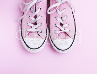 pair of old worn pink sneakers with white laces