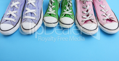 three pair of old worn textile sneakers on a blue background