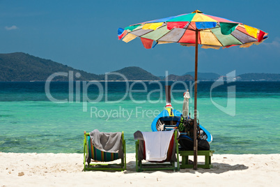 Beach umbrella chairs and boat in Coral island, Thailand