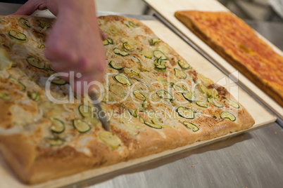 Pizza maker cutting italian pizza