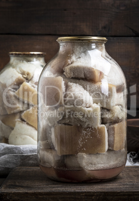 canned salted pieces of pork fat with meat in a large glass jar