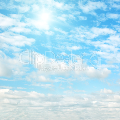 Sun on blue sky with white clouds.