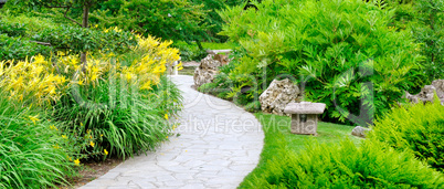 Summer park with paths and flowers. Wide photo.