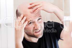 Bald man looking mirror at head baldness and hair loss