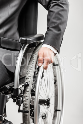 Invalid or disabled businessman in black suit sitting wheelchair