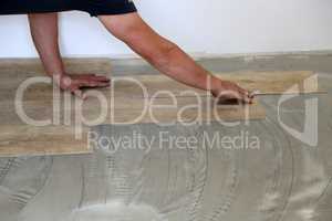 Work on laying flooring. Worker installing new vinyl tile floor.