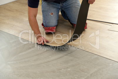 Work on laying flooring. Worker installing new vinyl tile floor.