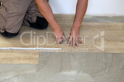 Work on laying flooring. Worker installing new vinyl tile floor.