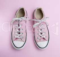 pair of old worn pink sneakers with white laces