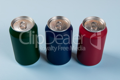 three colored cans of soft drinks closed on a light blue background