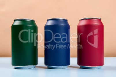 three colored cans of soft drinks closed on a light blue backgro