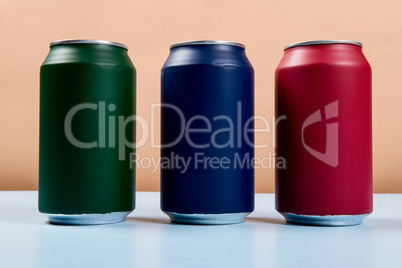 three colored cans of soft drinks closed on a light blue backgro
