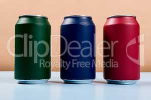 three colored cans of soft drinks closed on a light blue backgro