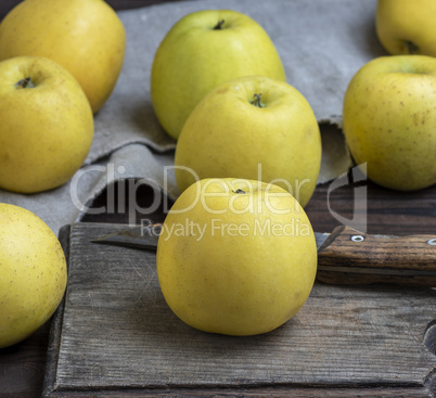 ripe whole yellow apples on a brown wooden board