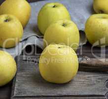 ripe whole yellow apples on a brown wooden board