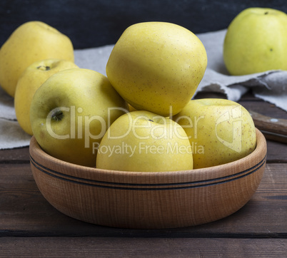 ripe whole yellow apples in a wooden bowl