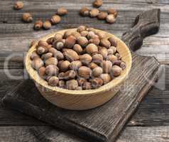 hazelnut nuts in a brown wooden bowl on a cutting board