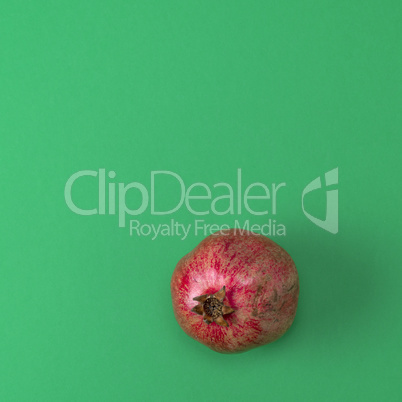 red pomegranate in the peel on a green background red pomegranate in the peel on a green background