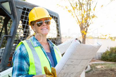 Smiling Female Worker Holding Technical Blueprints Near Jobsite