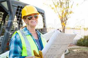 Smiling Female Worker Holding Technical Blueprints Near Jobsite