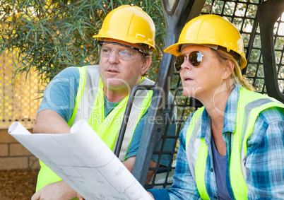 Male and Female Workers With Technical Blueprints Talking