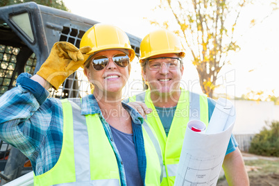 Male and Female Workers With Technical Blueprints at Jobsite