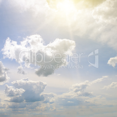 Sun on blue sky with white clouds.