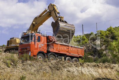 Excavator loads dump truck soil on the construction site