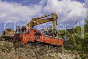 Excavator loads dump truck soil on the construction site