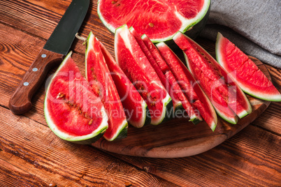 Watermelon half and slices lying on wooden table