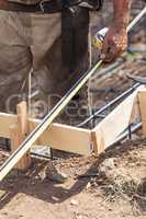 Worker Measuring Steel Rebar At Construction Site