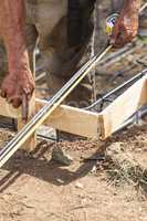 Worker Measuring Steel Rebar At Construction Site