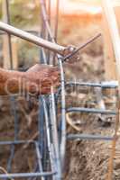 Worker Using Tools To Bend Steel Rebar At Construction Site