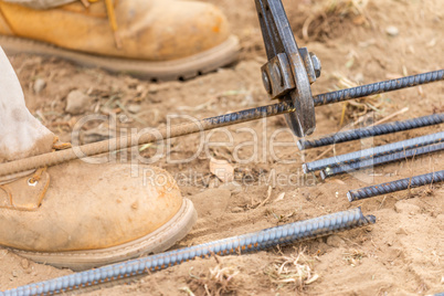Worker Cutting Steel Rebar At Construction Site