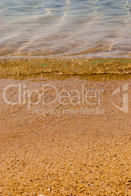 A small wave of blue sea on a sandy beach